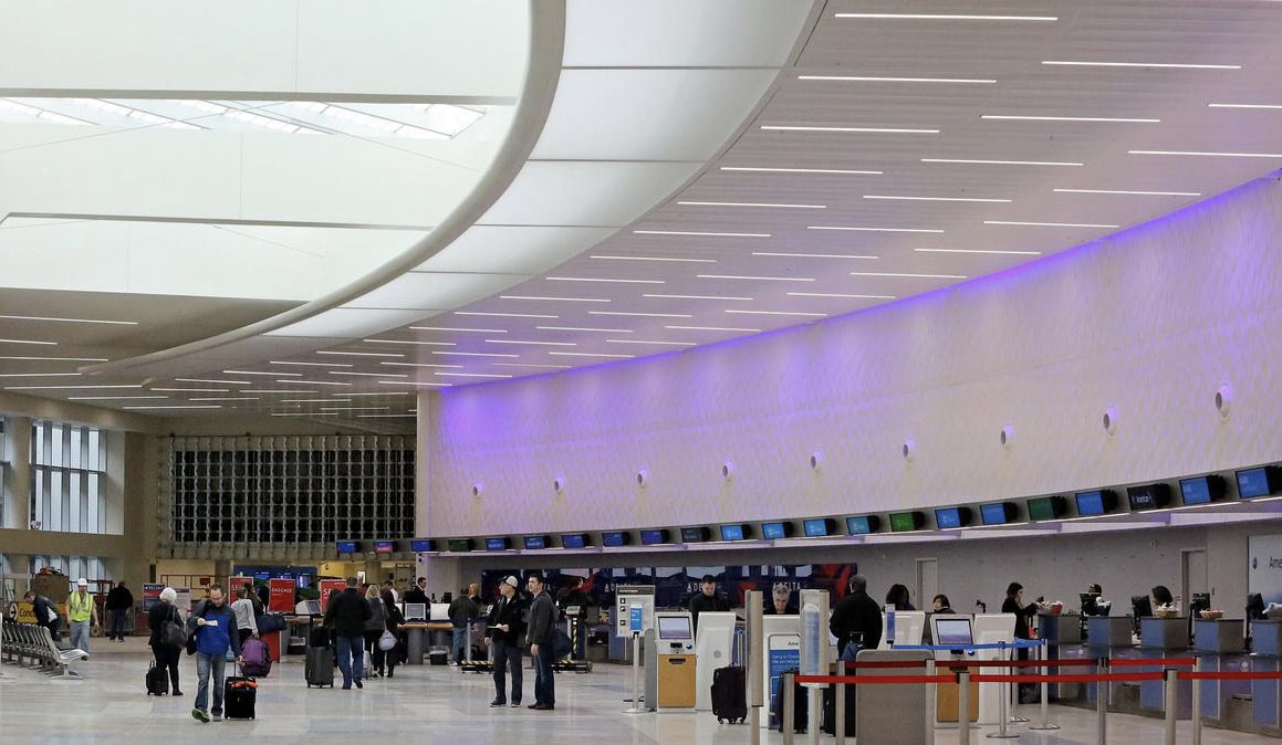 A busy airport check-in hall with passengers at ticket counters.