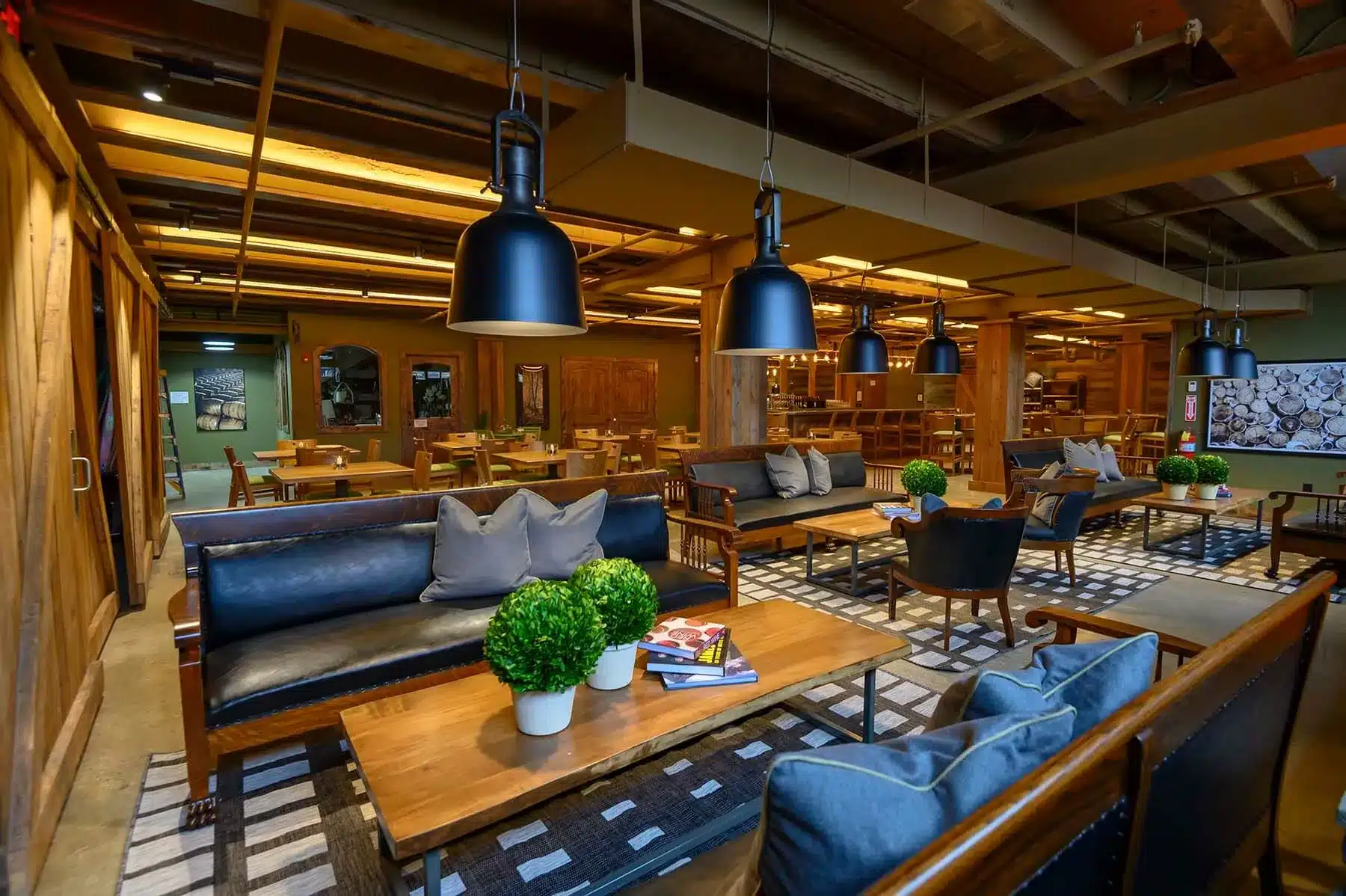 Rustic lounge area with wooden tables and chairs, leather sofas, and warm lighting