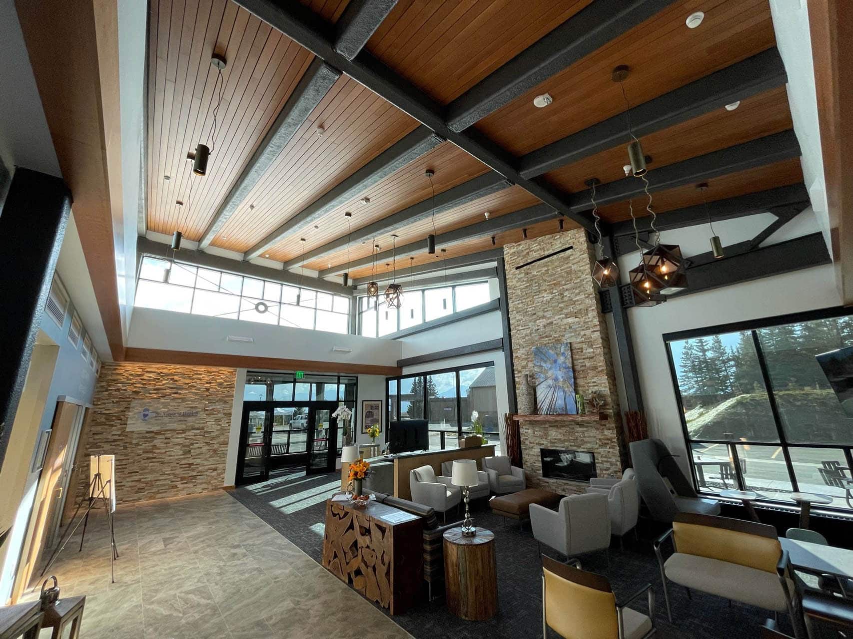 Modern waiting area of medical clinic with comfortable chairs, tall wood beam ceilings, and stone bricks walls