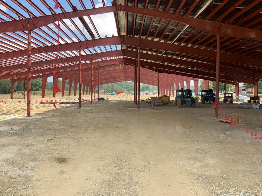 Steel-framed building under construction with exposed beams and construction equipment inside.